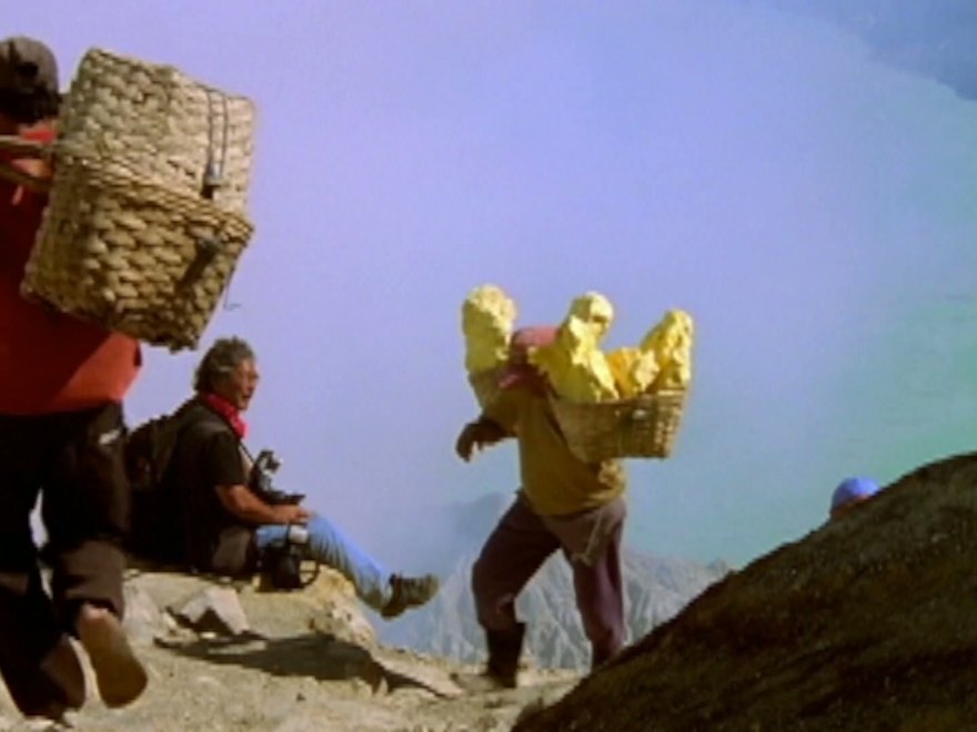 Porters carrying loaded baskets up a steep volcanic slope